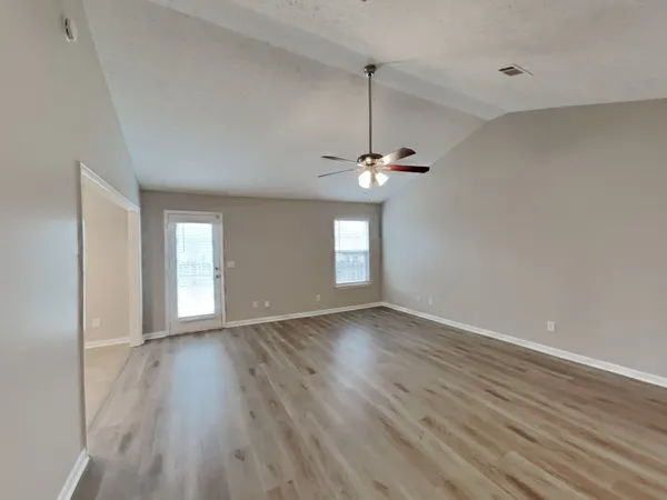 a view of an empty room with window and wooden floor