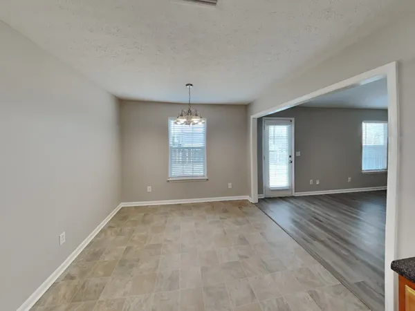 an empty room with chandelier fan and windows