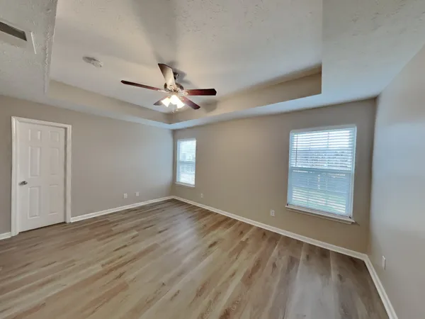 a view of an empty room with a window and wooden floor