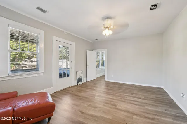 a view of an empty room with wooden floor and a window