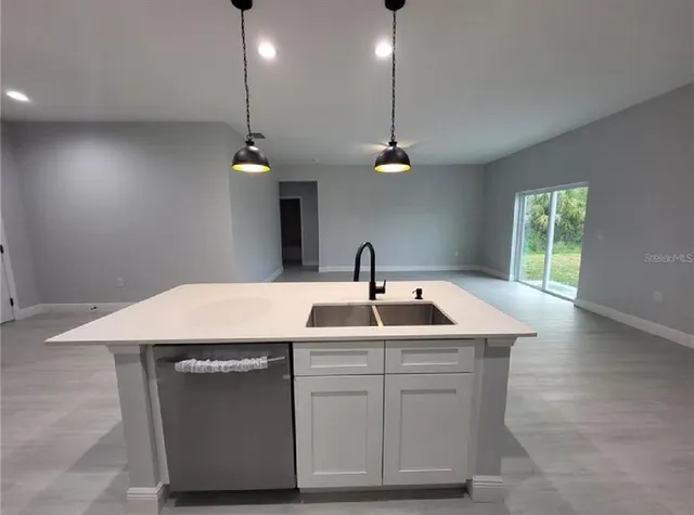 a kitchen with a sink a chandelier and wooden floor