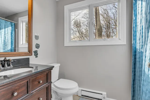 a bathroom with a granite countertop toilet a sink and a mirror