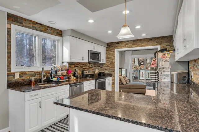 a kitchen with stainless steel appliances granite countertop sink stove and white cabinets