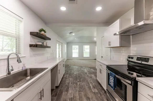 a kitchen with stainless steel appliances granite countertop a sink a stove and a wooden floors