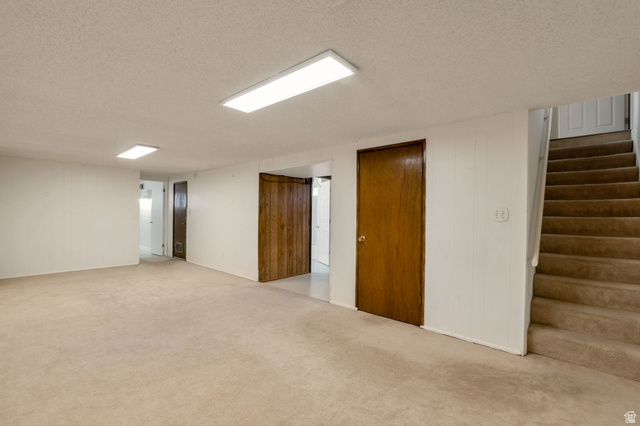447 550 South Bountiful, UT 84010 - Photo 16 of 25 Spacious carpeted room featuring white walls, flush-mount ceiling lighting, and a staircase with matching carpet