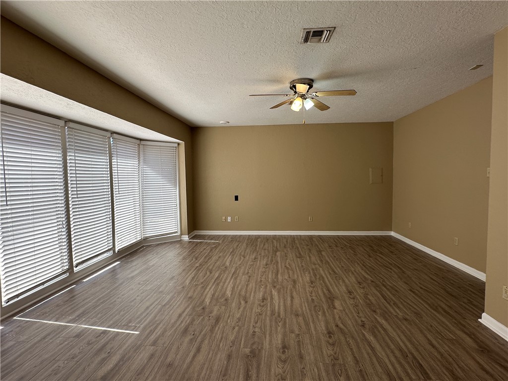 4705 Wooldridge Road Corpus Christi, TX 78413 - Photo 11 of 16 an empty room with wooden floor chandelier fan and windows
