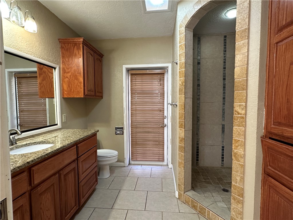 4705 Wooldridge Road Corpus Christi, TX 78413 - Photo 12 of 16 a bathroom with a granite countertop sink toilet and shower