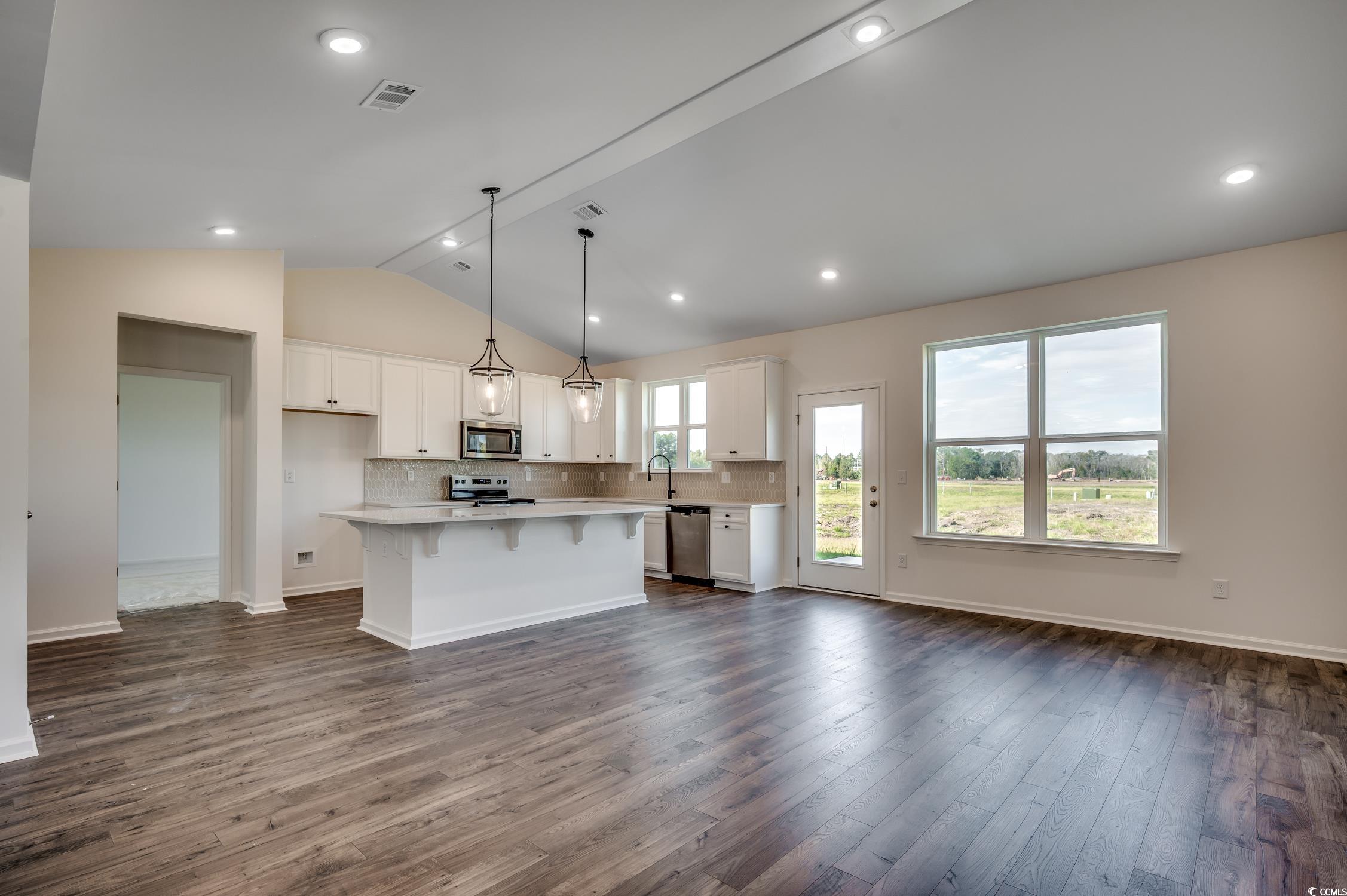 4004 Braid Court Myrtle Beach, SC 29588 - Photo 5 of 24 Kitchen with lofted ceiling, decorative backsplash, hanging light fixtures, white cabinetry, and a kitchen island