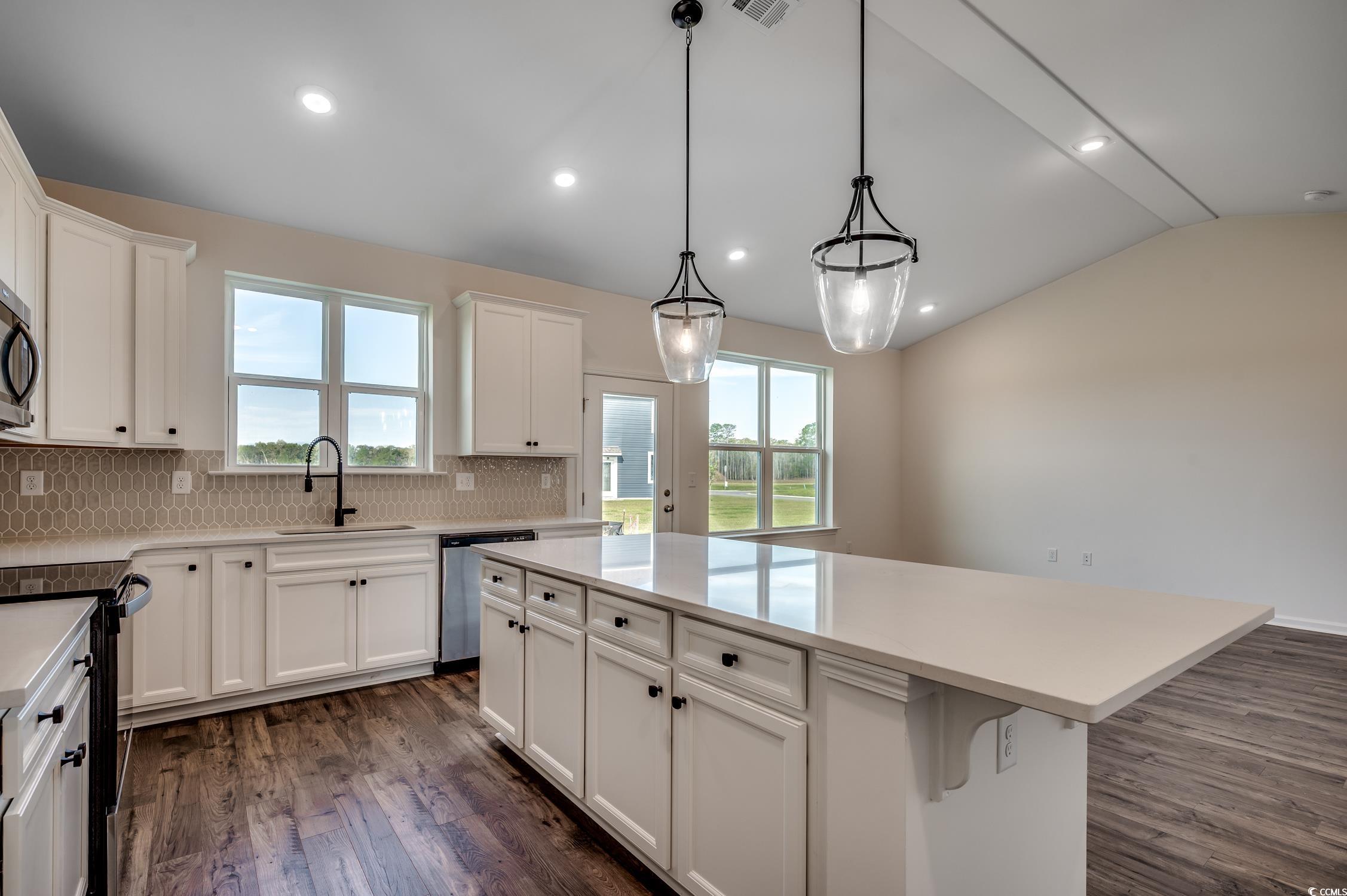 4004 Braid Court Myrtle Beach, SC 29588 - Photo 6 of 24 Kitchen with a center island, lofted ceiling, white cabinetry, dark wood-style flooring, and appliances with stainless steel finishes