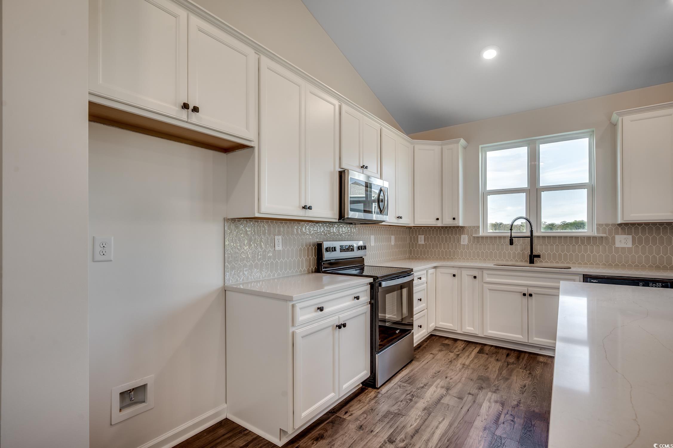4004 Braid Court Myrtle Beach, SC 29588 - Photo 7 of 24 Kitchen with appliances with stainless steel finishes, lofted ceiling, white cabinets, dark wood-style flooring, and tasteful backsplash