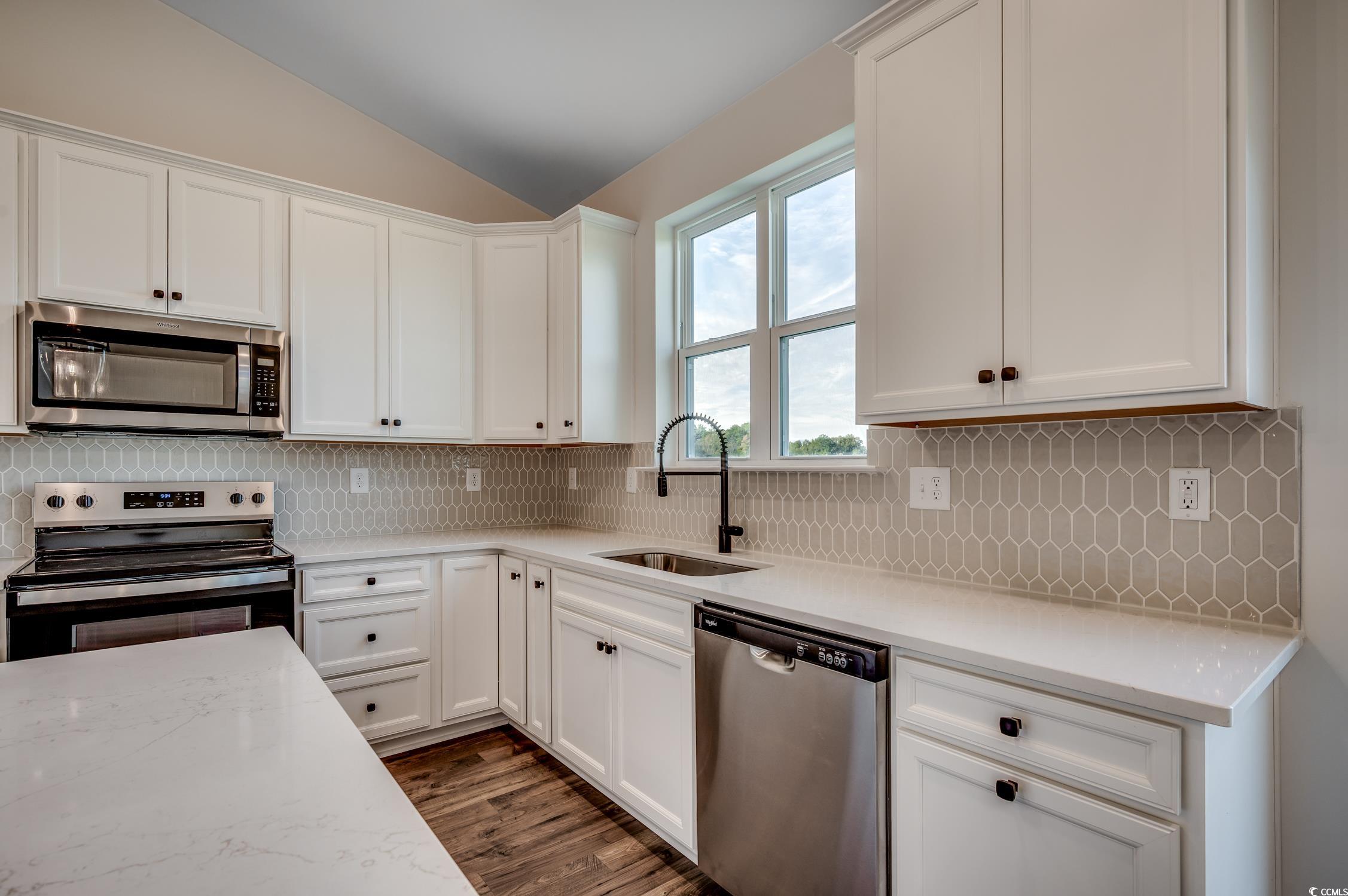4004 Braid Court Myrtle Beach, SC 29588 - Photo 8 of 24 Kitchen with stainless steel appliances, tasteful backsplash, white cabinetry, lofted ceiling, and light stone counters