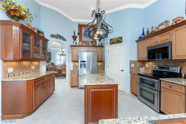a kitchen with stainless steel appliances granite countertop a refrigerator a stove top oven a sink dishwasher and a dining table with the view