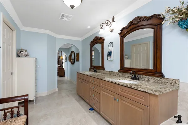 a bathroom with a granite countertop sink two mirror and a shower