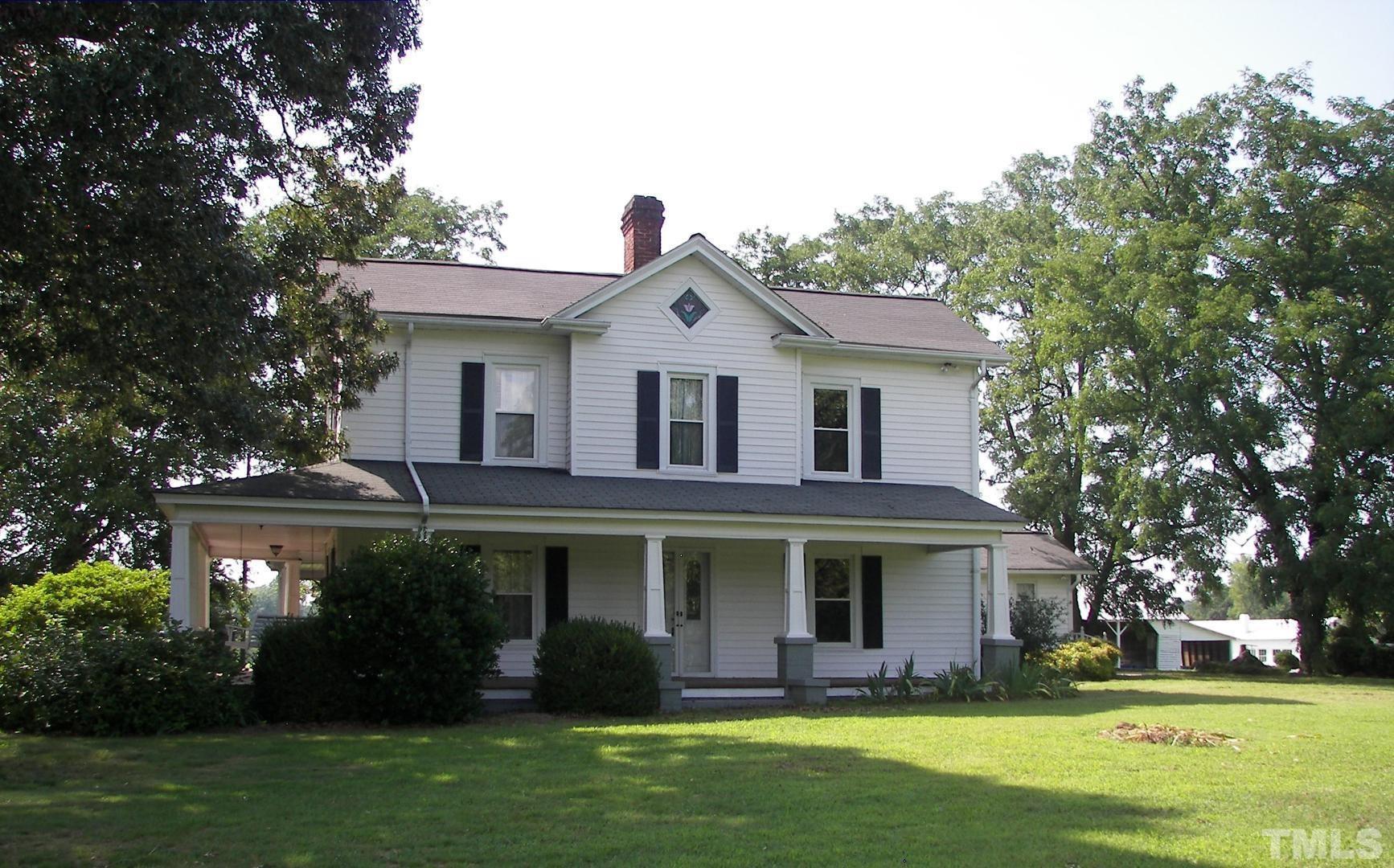 a front view of a house with garden and trees