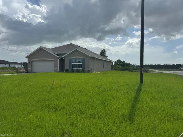 a view of a house with a big yard and a large tree