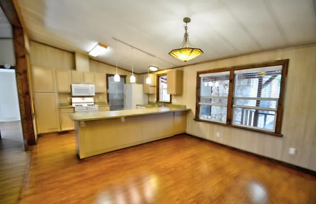 a kitchen with refrigerator a stove a sink dishwasher and wooden cabinets with wooden floor