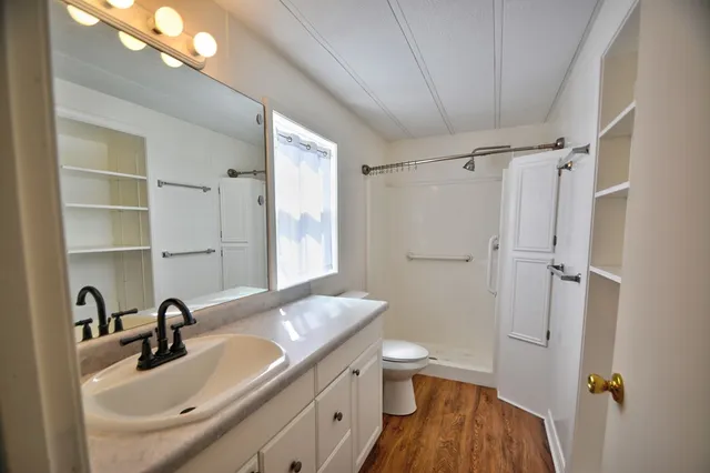 a bathroom with a sink a toilet a mirror and shower