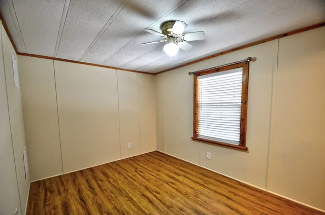 a view of an empty room with a window and wooden floor