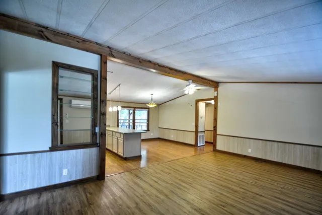 a view of an empty room with wooden floor and windows