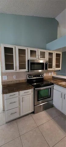 a kitchen with granite countertop a stove microwave and cabinets