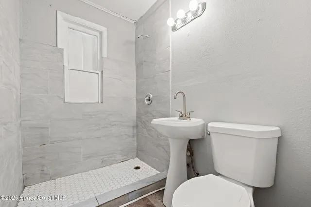 a bathroom with a sink a toilet and shower
