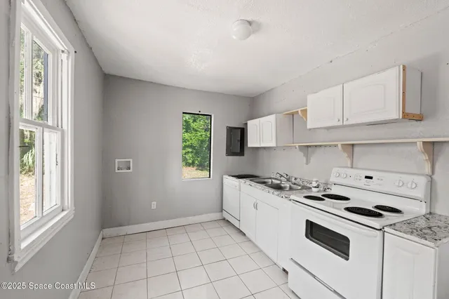 a kitchen with granite countertop a stove a sink dishwasher and white cabinets with wooden floor