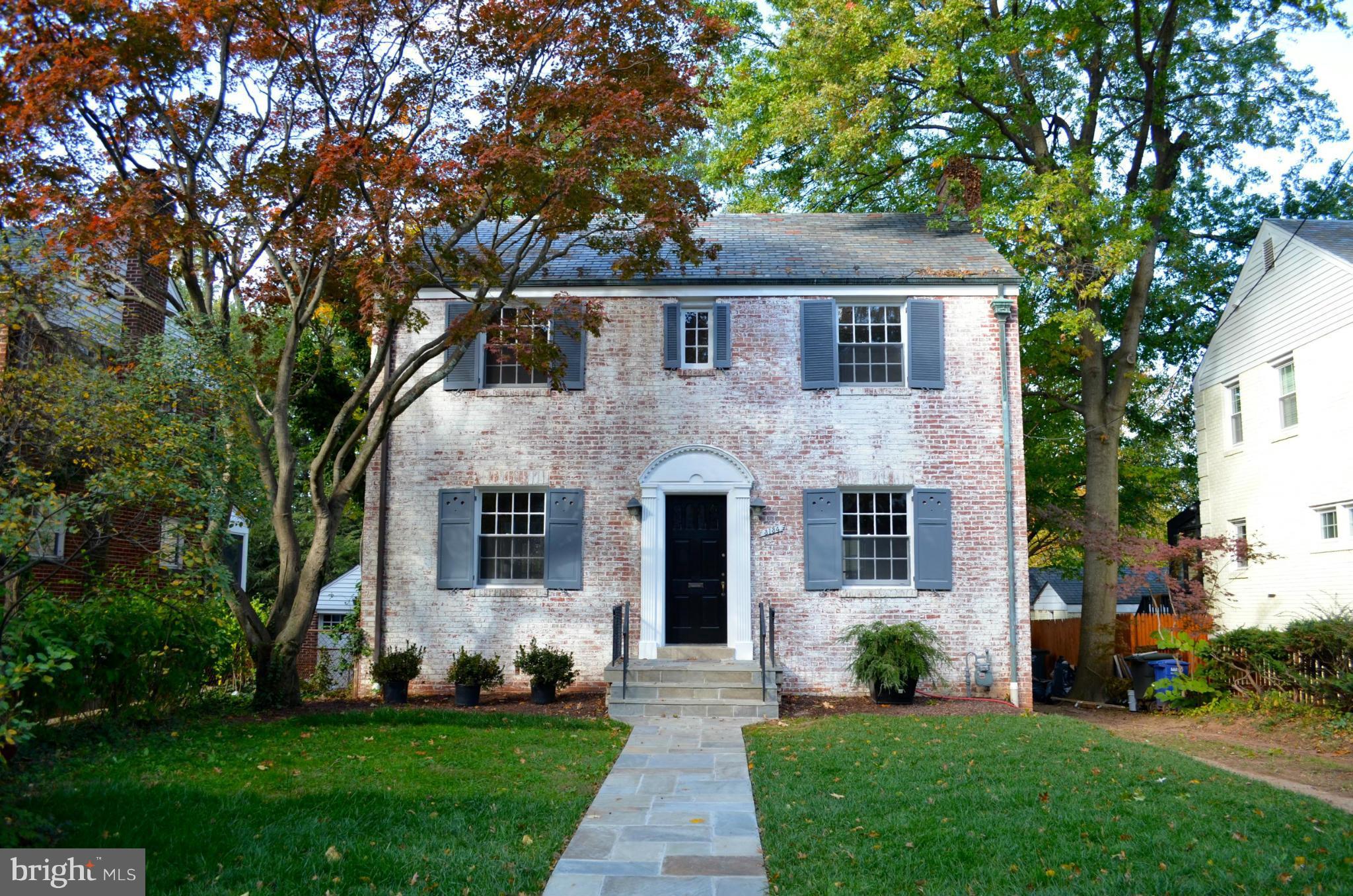 a front view of a house with a yard and trees