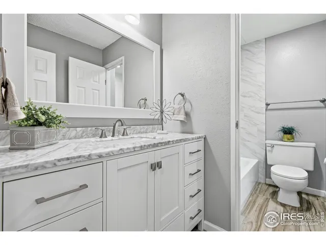 a bathroom with a granite countertop sink a toilet and a mirror