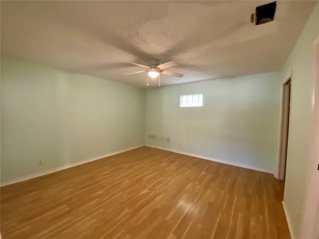 an empty room with a ceiling fan and wooden floor