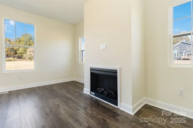 an empty room with wooden floor fireplace and windows