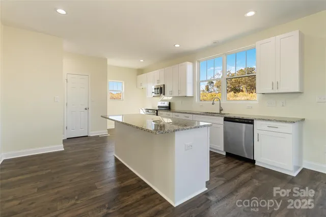 a kitchen with stainless steel appliances granite countertop wooden cabinets a sink and dishwasher with wooden floor