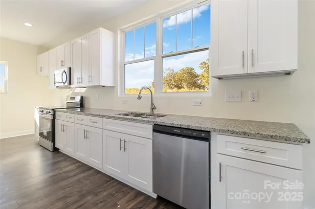 a kitchen with granite countertop white cabinets white appliances and sink