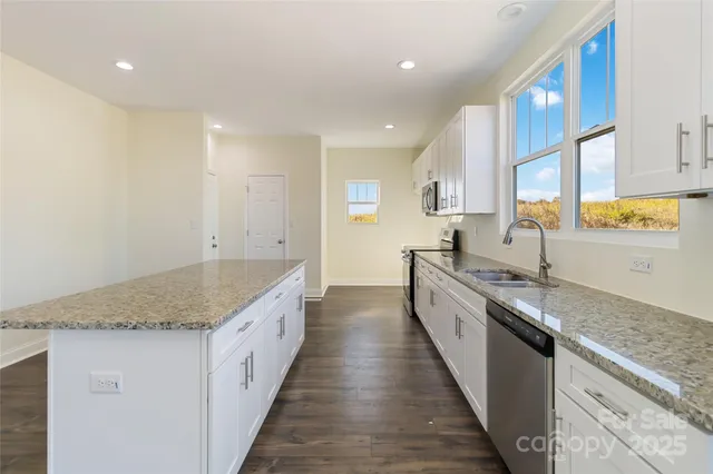 a large kitchen with granite countertop a sink and a stove