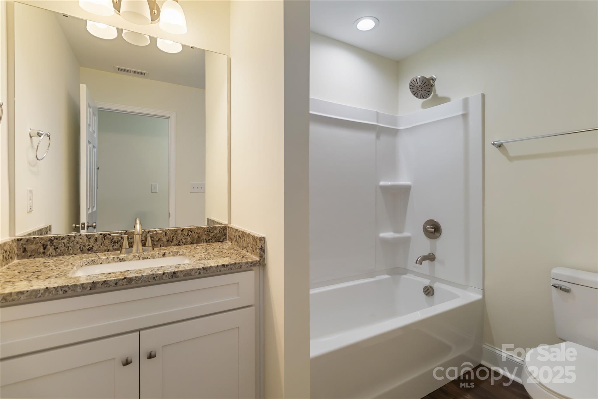 1012 Heath Helms Road Monroe, NC 28110 - Photo 28 of 48 a bathroom with a granite countertop sink a mirror a bathtub and shower