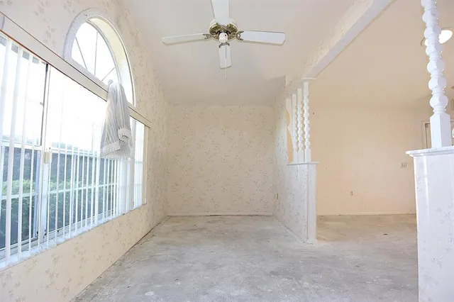 en empty room with windows and ceiling fan