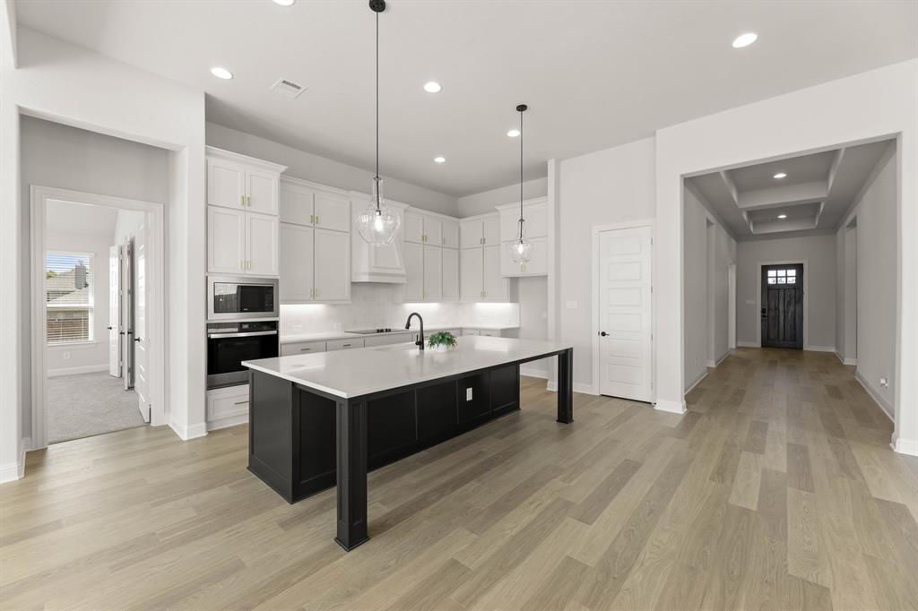 5210 Rowlan Row Midlothian, TX 76065 - Photo 29 of 40 a large kitchen with a center island wooden floor stainless steel appliances and a center island