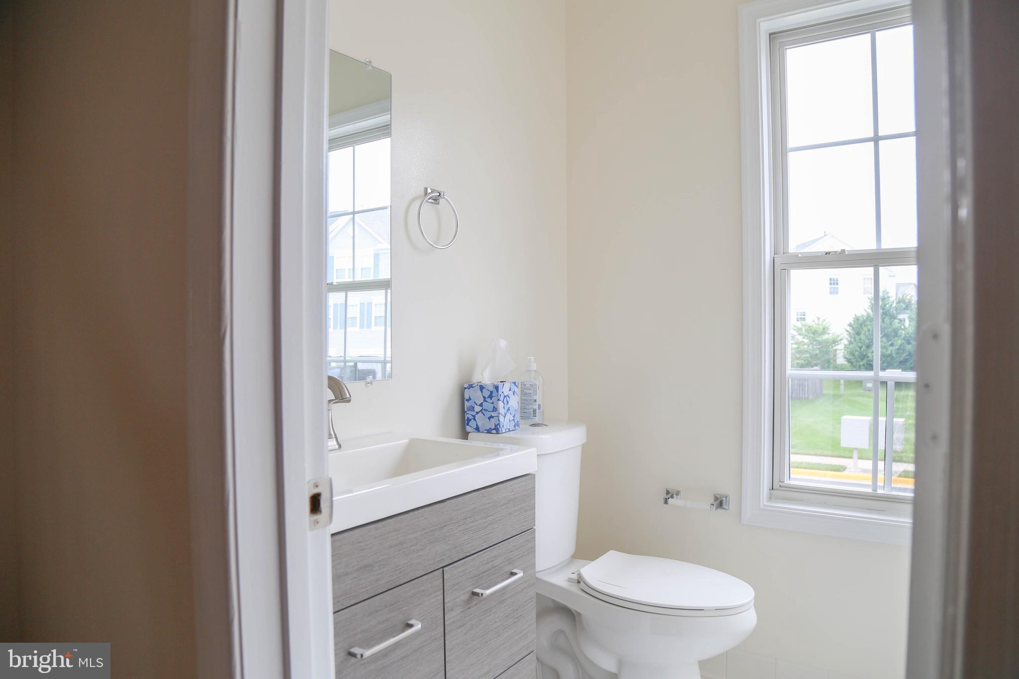 8461 Tackhouse Loop Gainesville, VA 20155 - Photo 4 of 39 a bathroom with a toilet a sink a mirror and a window