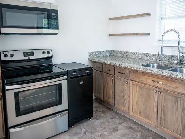a kitchen with granite countertop cabinets stainless steel appliances and wooden floor