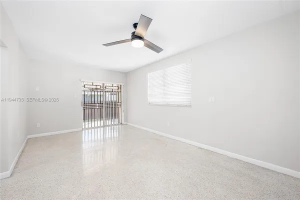 an empty room with wooden floor fan and windows