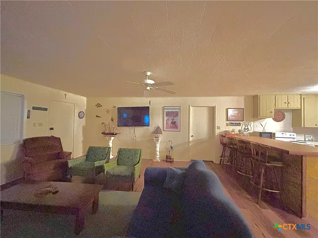 a living room with couches and kitchen view with wooden floor