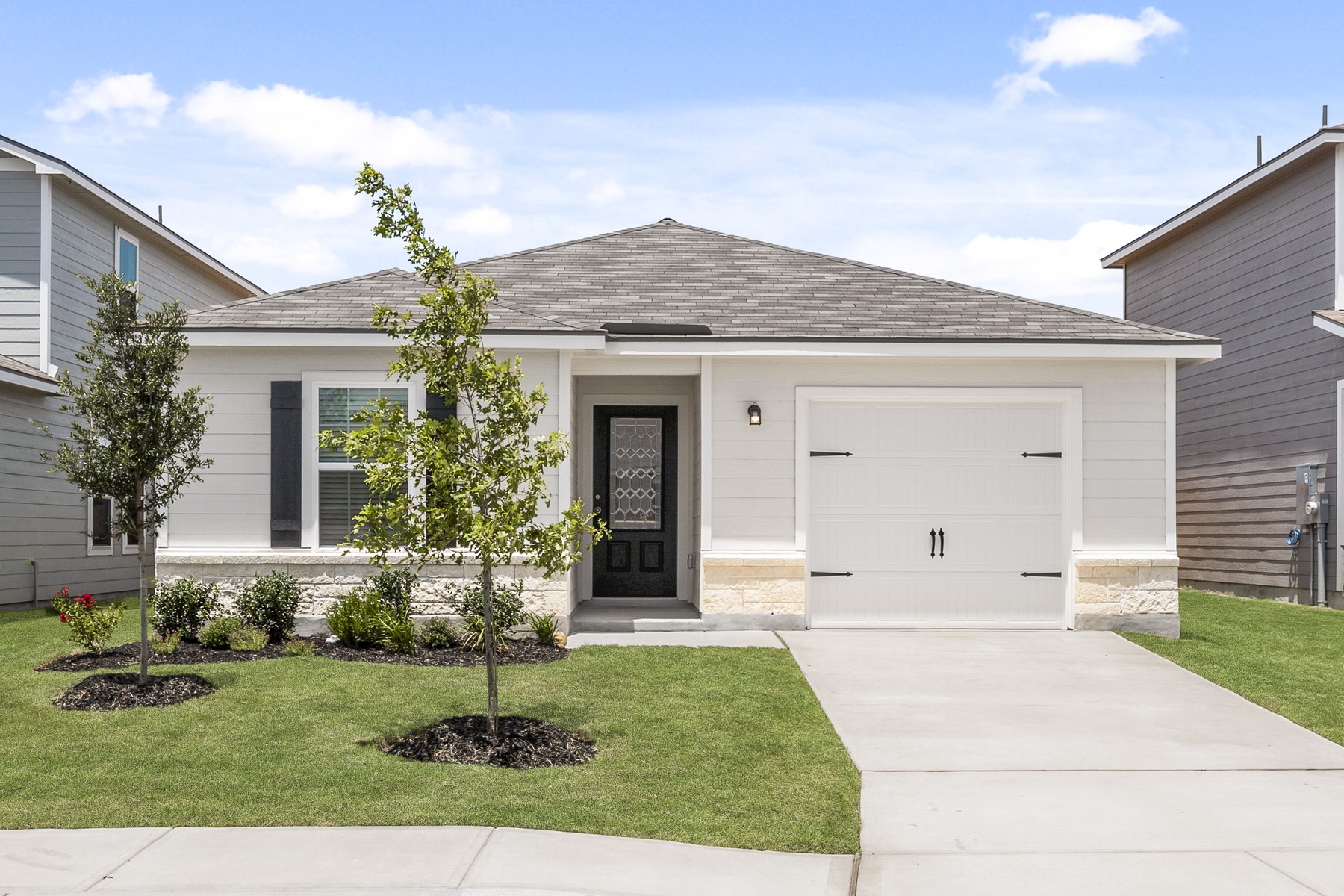 Single story home featuring roof with shingles, a front yard, stone siding, driveway, and an attached garage