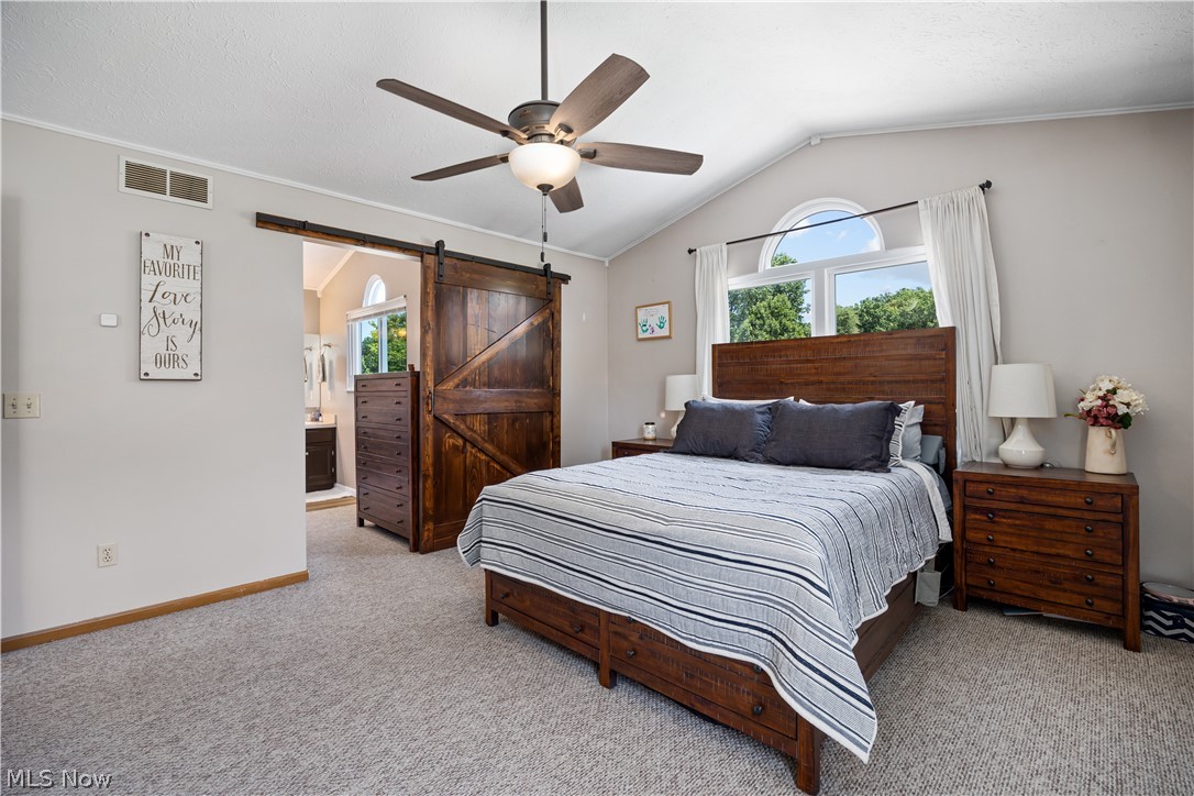 684 Guilford Road Vermilion, OH 44089 - Photo 22 of 37 Bedroom with multiple windows, ceiling fan, connected bathroom, and a barn door