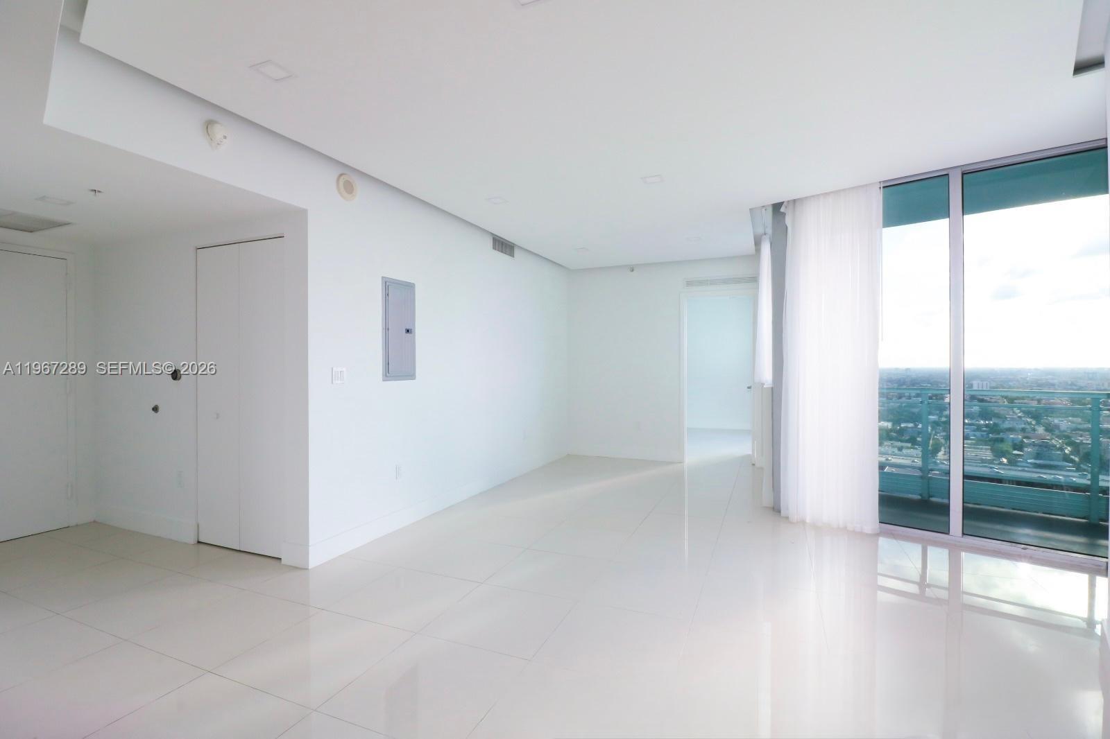 92 Southwest 3rd Street, Unit 2706 Miami, FL 33130 - Photo 2 of 13 a view of an empty room with wooden floor and a window