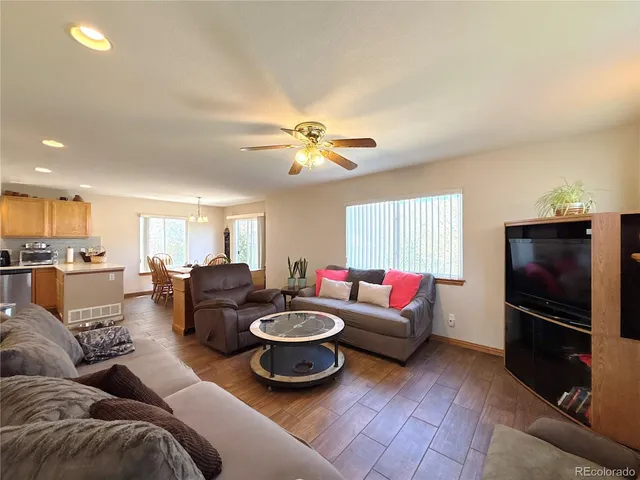 a living room with furniture and a flat screen tv with kitchen view