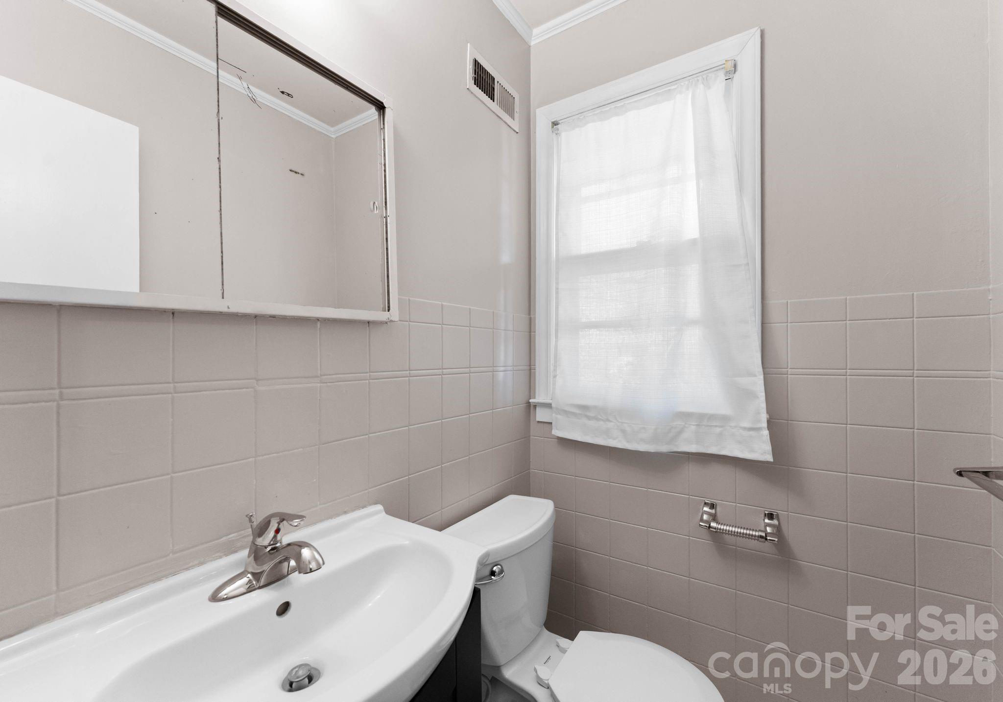 1136 East Woodlawn Road Charlotte, NC 28209 - Photo 34 of 47 a bathroom with a sink a toilet and mirror