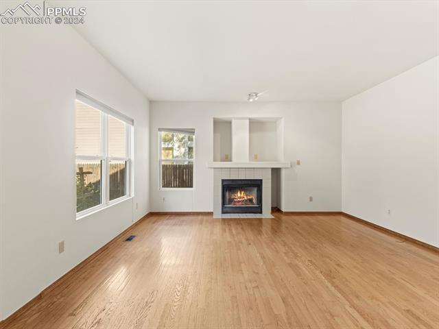 7590 Julynn Road Colorado Springs, CO 80919 - Photo 20 of 44 Unfurnished living room featuring light hardwood / wood-style floors and a tiled fireplace