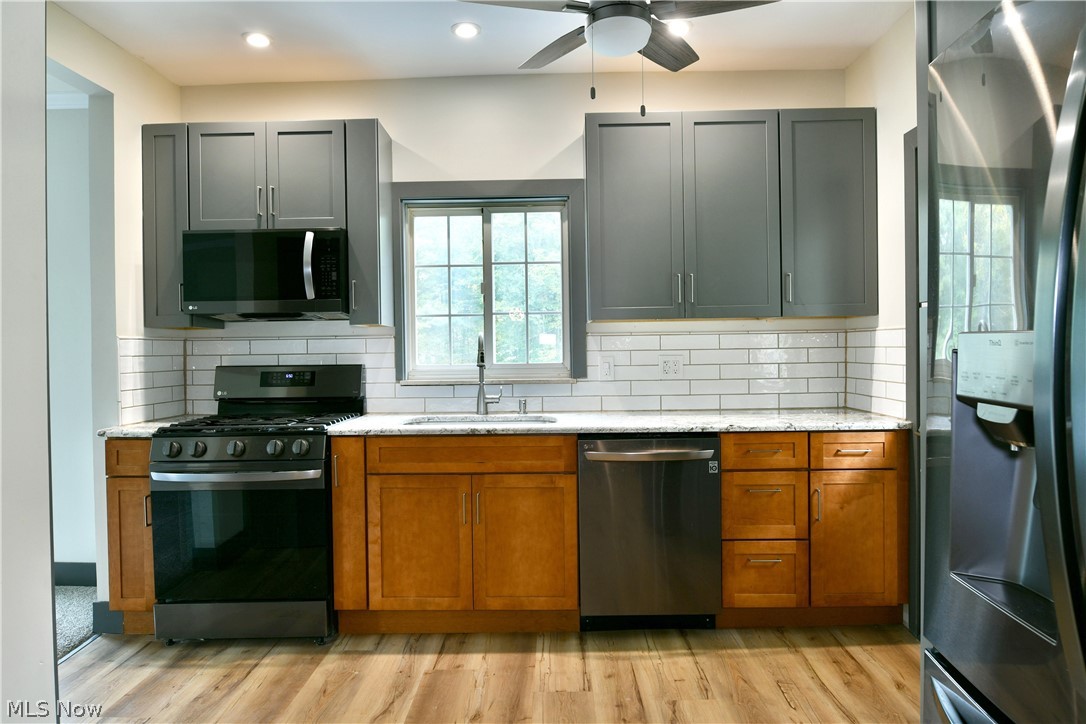 892 Yankee Run Road Masury, OH 44438 - Photo 18 of 50 Modern kitchen featuring wood-finish flooring, two-tone cabinetry, white subway tile backsplash, and stainless steel appliances