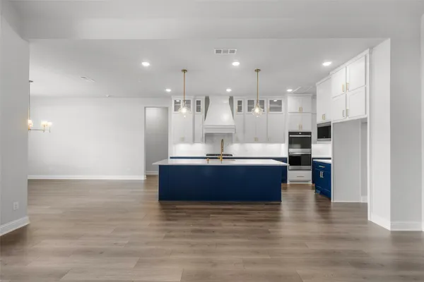 a large room with kitchen island a sink wooden floor and a counter top space
