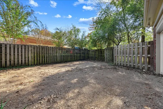 a view of backyard with wooden fence and trees