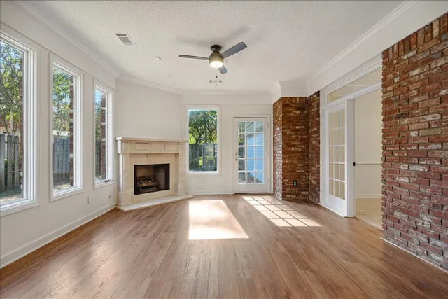 a view of an empty room with wooden floor fireplace and a window